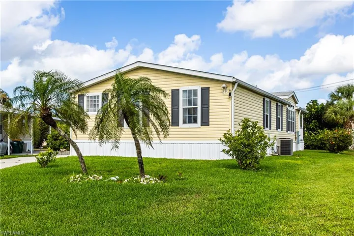 View of side of property with a lawn and central AC