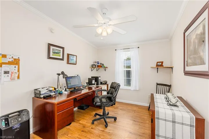 Home office featuring ceiling fan, crown molding, light wood finished floors, and baseboards