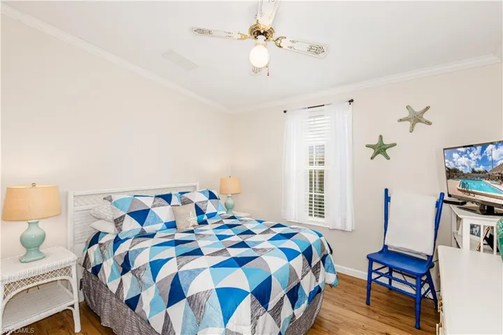 Bedroom with ceiling fan, baseboards, crown molding, and wood finished floors