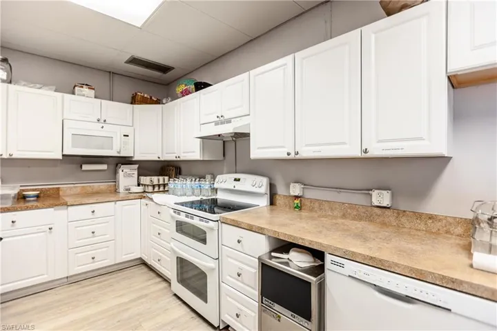 Kitchen featuring a paneled ceiling, light wood-style floors, white appliances, visible vents, and under cabinet range hood