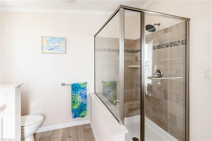 Full bath with a shower stall, crown molding, and baseboards