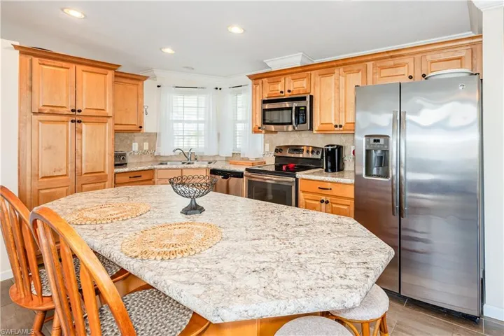 Kitchen with appliances with stainless steel finishes, a breakfast bar, a kitchen island, decorative backsplash, and a sink