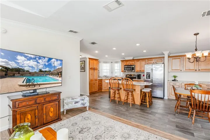 Dining room featuring an inviting chandelier, visible vents, ornamental molding, and wood finished floors