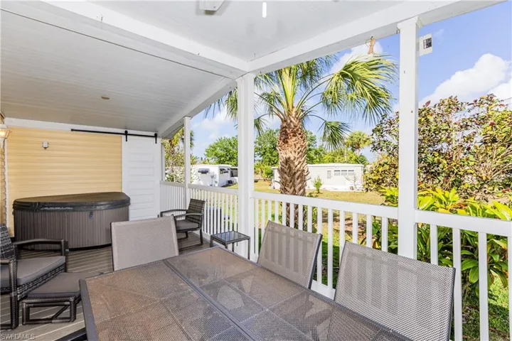 View of patio featuring outdoor dining area, a wooden deck, and a hot tub