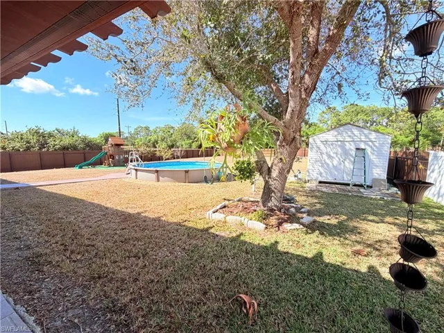 Fenced backyard with a shed, a playground, and a patio