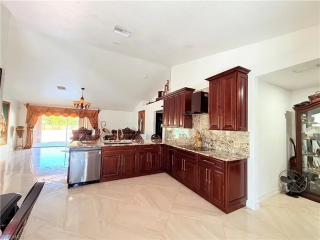 Kitchen featuring a peninsula, light stone countertops, dishwasher, open floor plan, and a chandelier