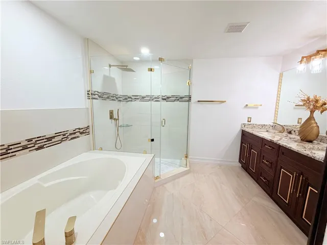 Full bathroom featuring a garden tub, double vanity, and a stall shower