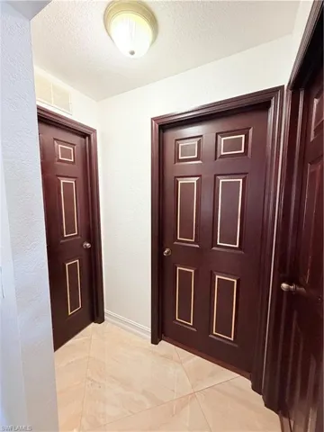 Hallway featuring a textured wall and a textured ceiling