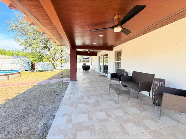 Fenced backyard featuring a ceiling fan, a patio, and an outdoor structure