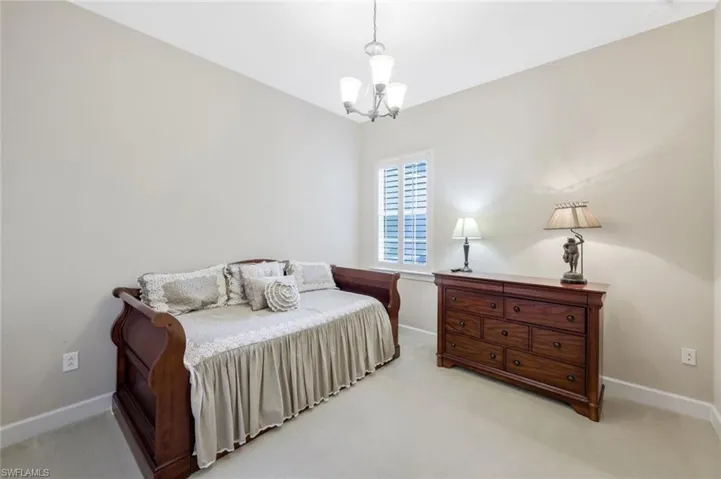 Bedroom featuring a chandelier and light carpet