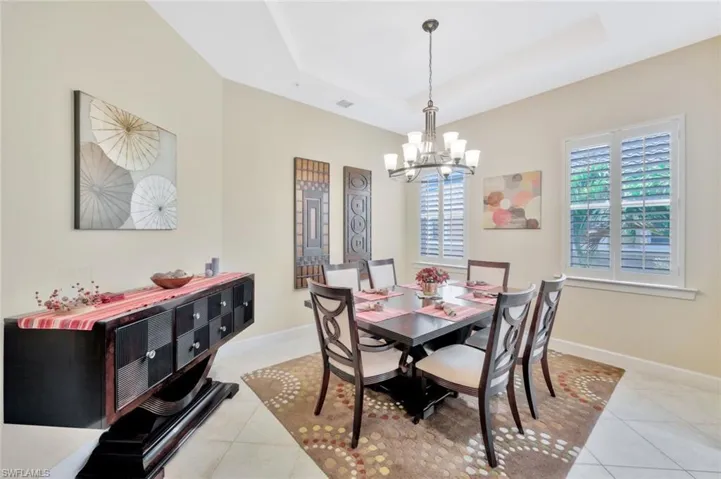 Dining room with a chandelier, tile patterned floors, and a tray ceiling
