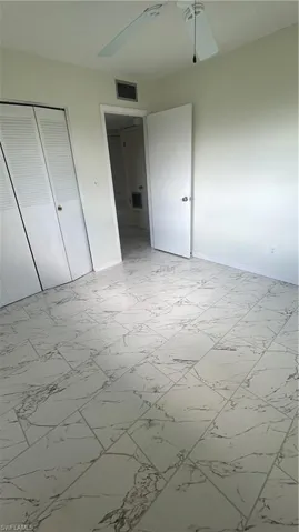 Unfurnished bedroom featuring a closet, ceiling fan, marble finish floor, baseboards, and visible vents