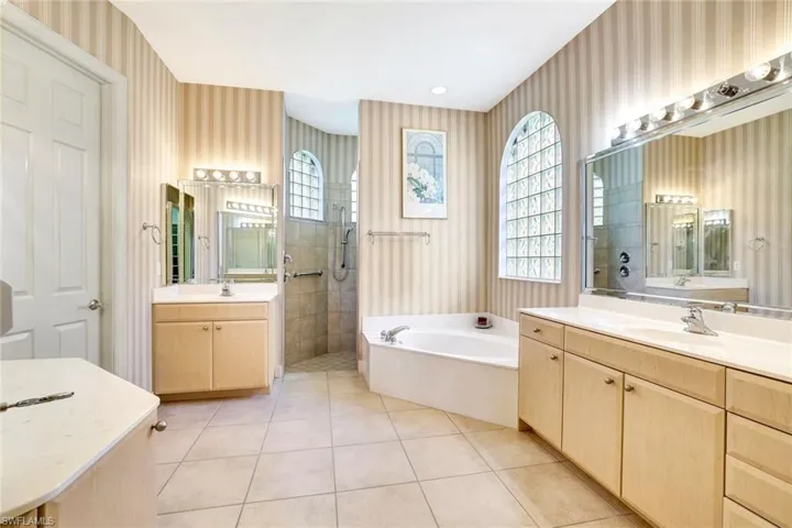 The primary bathroom has tile flooring, double vanity each with a sink, tub and a shower with multiple shower heads