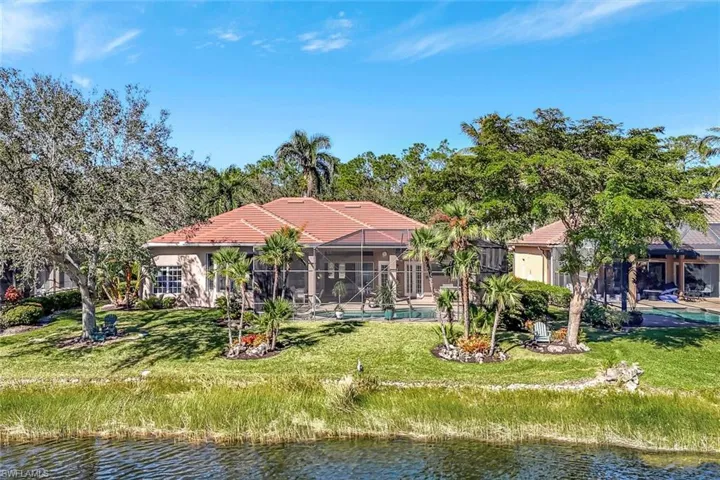 Rear view of house featuring screened-in enclosure, heated pool, spa, summer kitchen and an amazing water view.