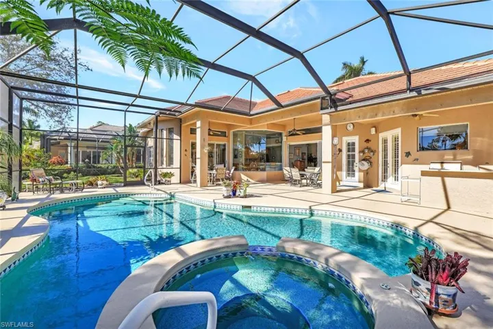 Screen enclosed lanai with heated pool, in-ground spa, and summer kitchen with grill