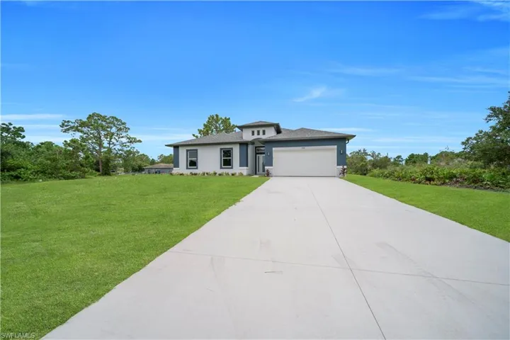 Prairie-style house with a front yard, a garage, stucco siding, and driveway