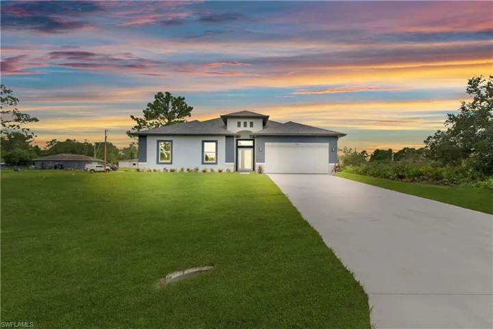 Prairie-style house featuring concrete driveway, stucco siding, a yard, an attached garage, and roof with shingles