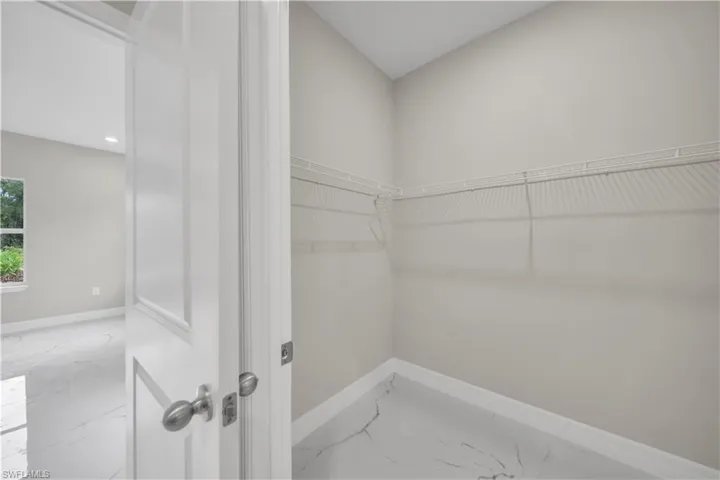 Walk in closet featuring light marble finish flooring