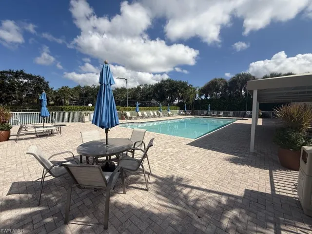 Community pool with a patio area and view of scattered trees
