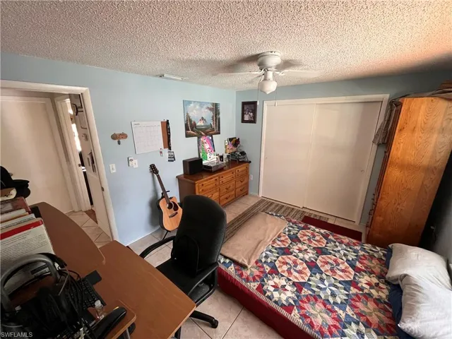 Home office with light tile patterned floors, a textured ceiling, and ceiling fan