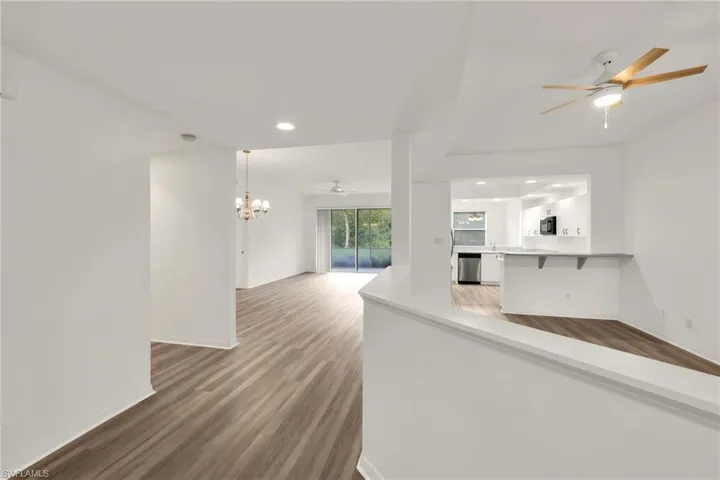 Unfurnished living room featuring ceiling fan, wood finished floors, a chandelier, and recessed lighting