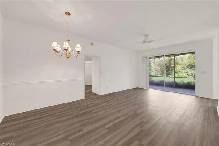 Spare room featuring wood finished floors, a chandelier, and a ceiling fan