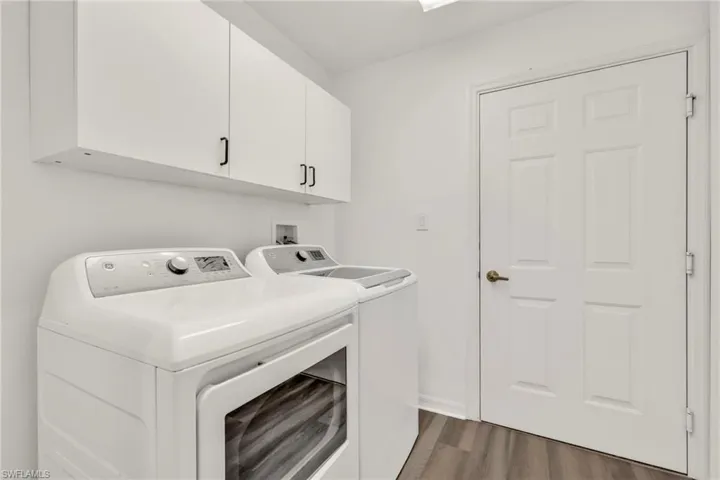 Laundry room with washing machine and dryer, wood finished floors, and cabinet space