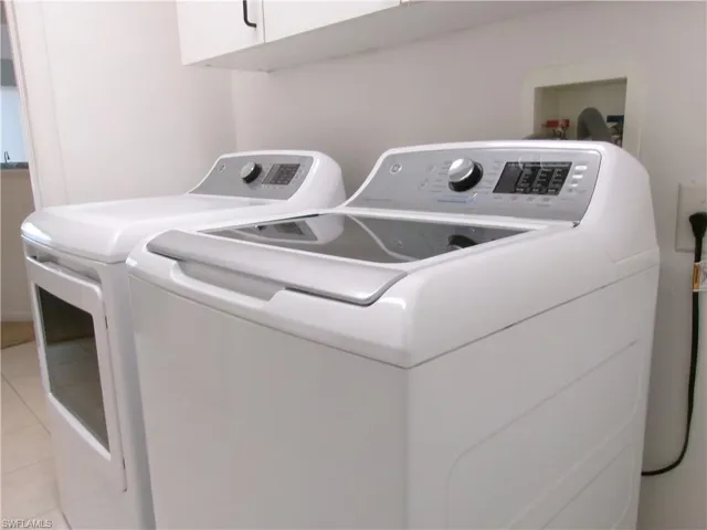 Laundry room featuring separate washer and dryer, cabinet space, and light tile patterned floors