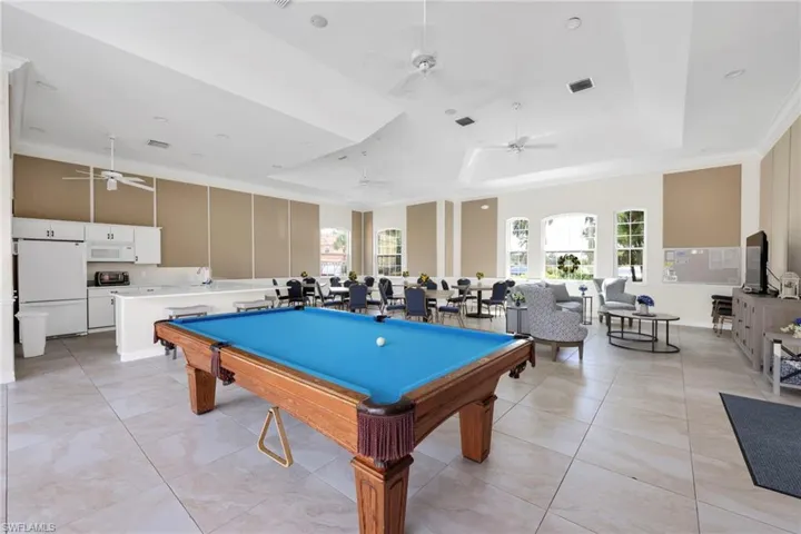 Playroom with a ceiling fan, billiards, a tray ceiling, light tile patterned floors, and crown molding