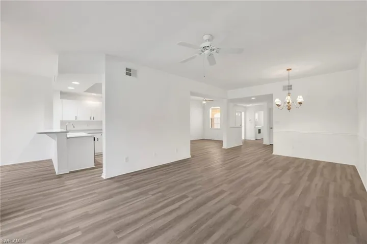 Unfurnished living room featuring a chandelier, light wood-style flooring, ceiling fan, and recessed lighting