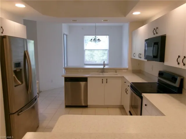 Kitchen with appliances with stainless steel finishes, a sink, recessed lighting, light countertops, and a peninsula