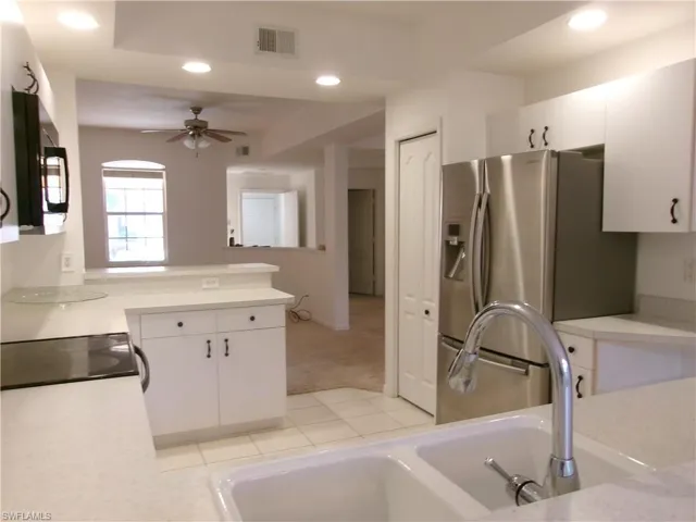 Kitchen with a sink, recessed lighting, black microwave, light countertops, and stainless steel fridge with ice dispenser