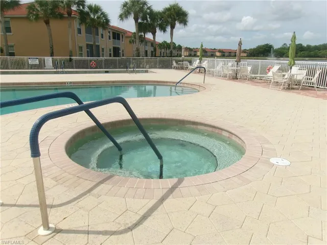 Community pool with fence, a patio area, and a hot tub