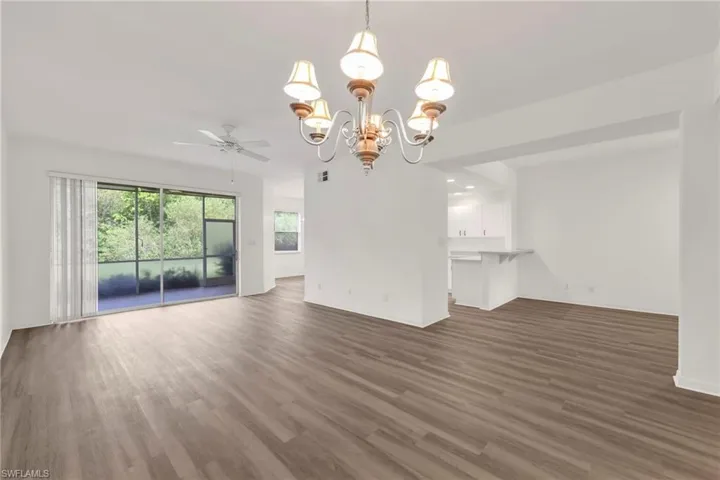Unfurnished living room featuring wood finished floors, a ceiling fan, and a chandelier