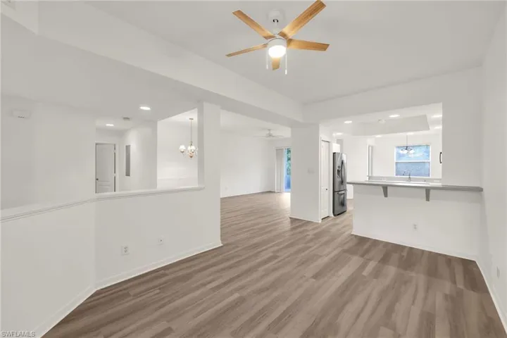 Unfurnished living room with a chandelier, wood finished floors, ceiling fan, and recessed lighting