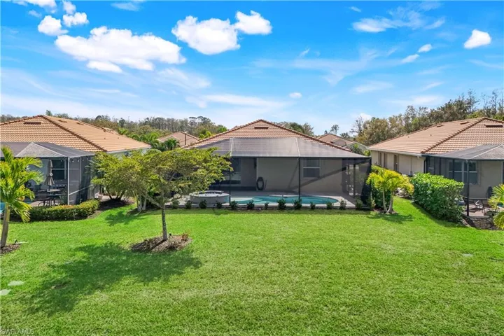 Back of property with a lanai, an outdoor pool, a tiled roof, and a lawn