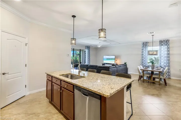 Kitchen featuring visible vents, hanging light fixtures, stainless steel dishwasher, ornamental molding, and a sink