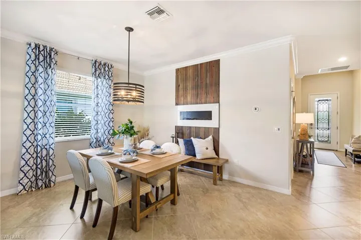 Dining space featuring ornamental molding, visible vents, and baseboards and wall fireplace
