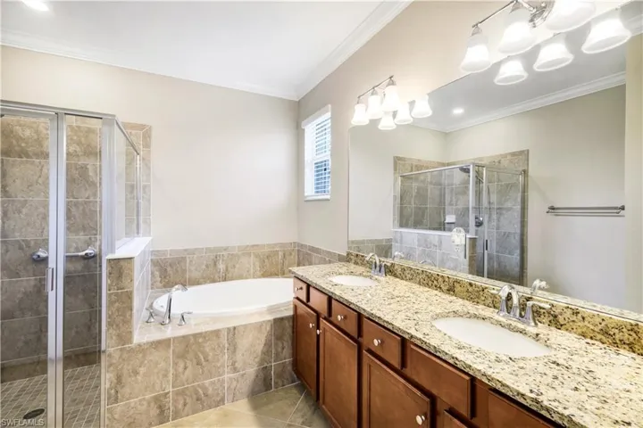 Full Master bath with a bath, a stall shower, crown molding, and a sink