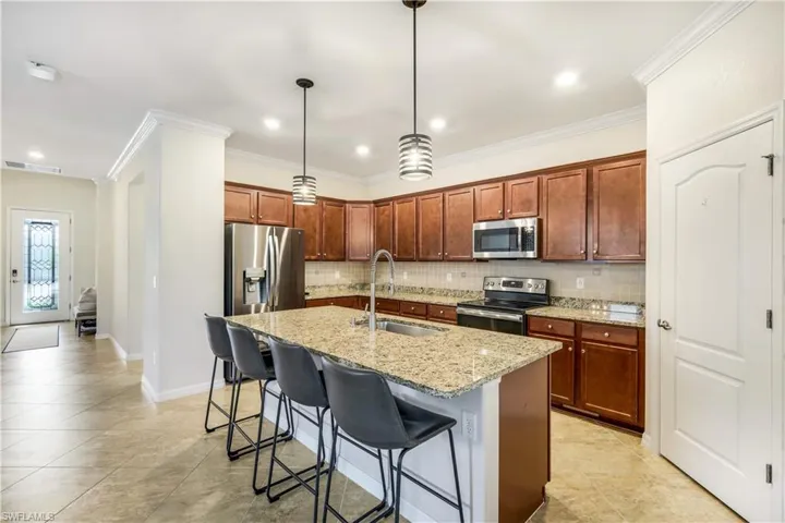 Kitchen with light granite counters, a breakfast bar, backsplash, appliances with stainless steel finishes, and a sink