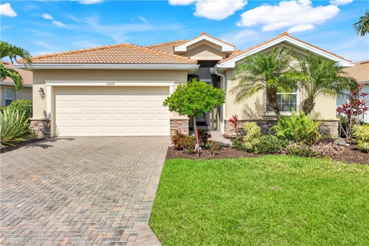 View of front of property featuring a garage, stone siding, decorative driveway, and stucco siding