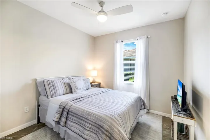 Tiled second bedroom featuring a ceiling fan and baseboards