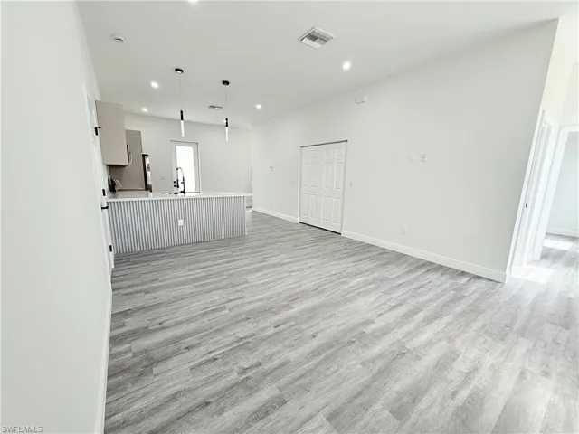 Unfurnished living room with sink and light hardwood / wood-style flooring