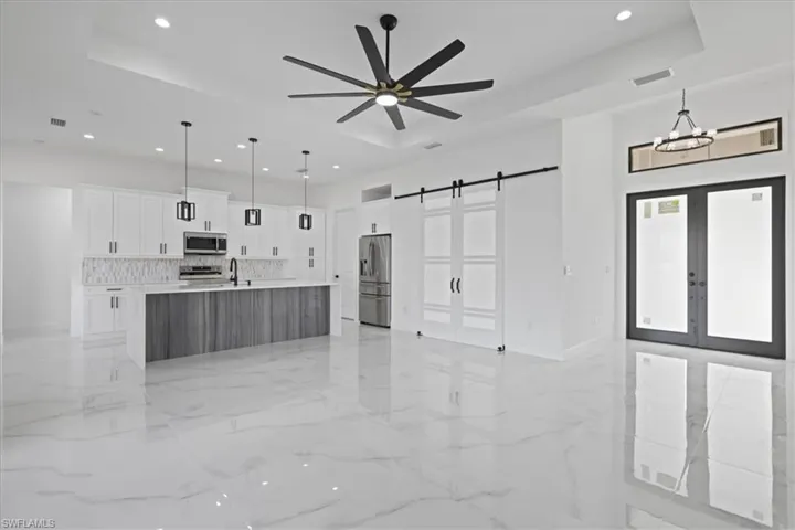 another view of Kitchen with decorative light fixtures, white cabinetry, french doors, a barn door (office entry), and open floor plan