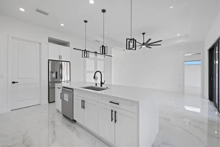 Kitchen featuring white cabinetry, hanging light fixtures, recessed lighting, quartz countertops, and a kitchen island with sink
