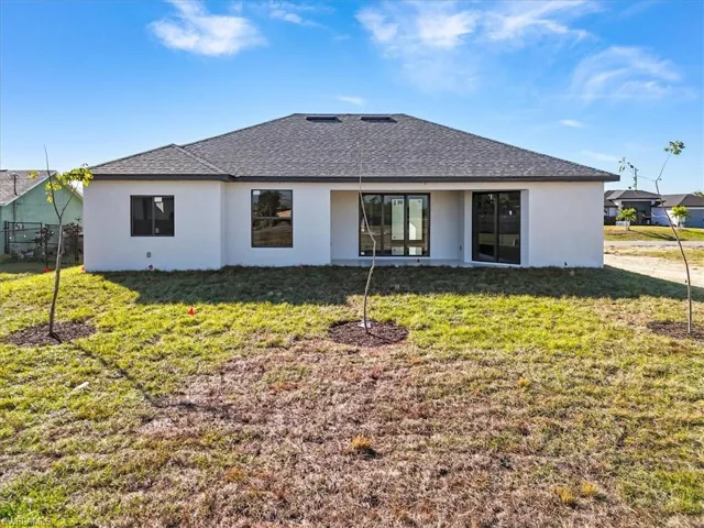 Back of property featuring roof with shingles, stucco siding, and a patio