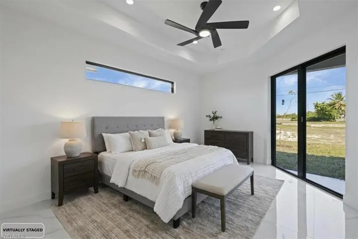 Photo Staged. Primary Bedroom with access to outside, a tray ceiling, a ceiling fan, and recessed lighting