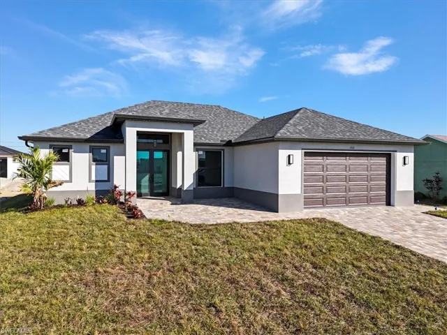 Prairie-style home with stucco siding, a front lawn, french doors, decorative driveway, and a shingled roof