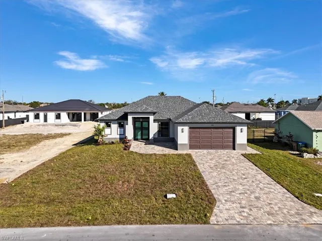 View of front of home with stucco siding, a residential view, decorative driveway, and an attached garage