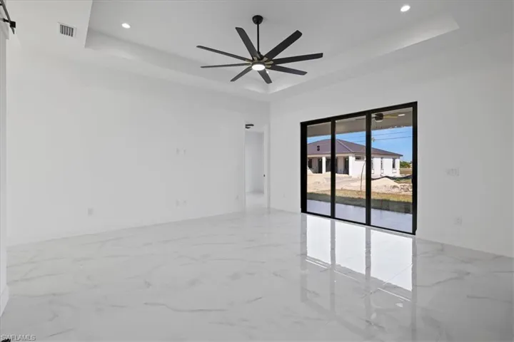 Living Room with a tray ceiling, ceramic finish flooring, and recessed lighting view to the backyard.